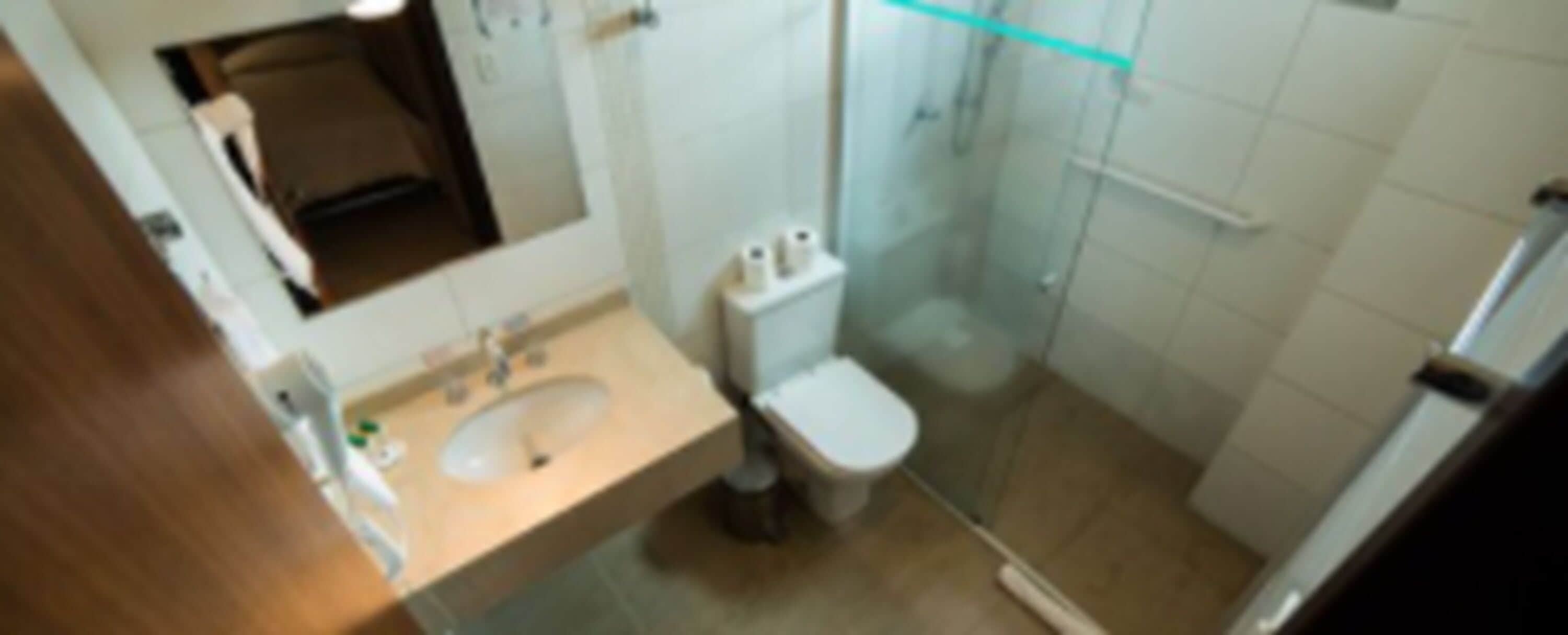 A bathroom with a sink, toilet, and glass shower enclosure.