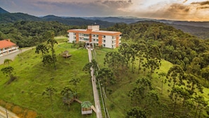 A large building surrounded by lush greenery and hills.