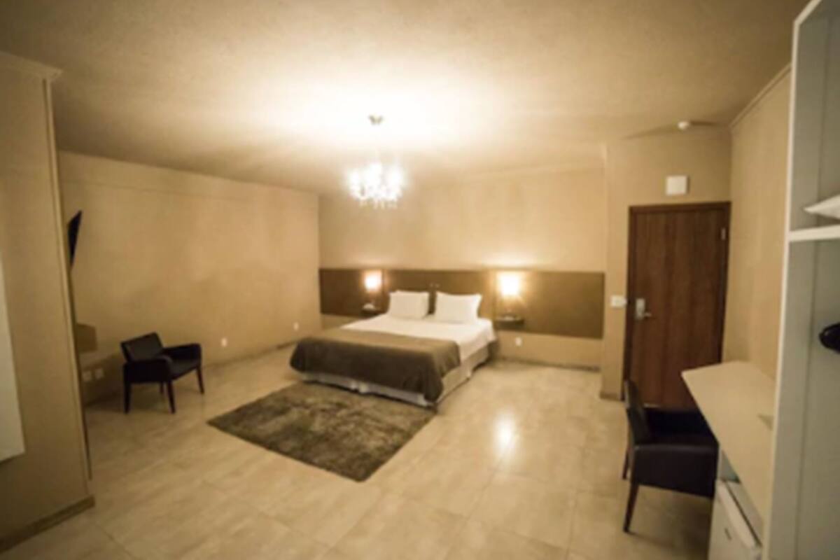 Un dormitorio con cama, mesitas de noche, escritorio y silla.