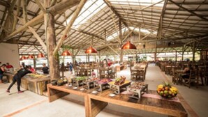 An indoor market with wooden tables and chairs, and a variety of goods displayed.