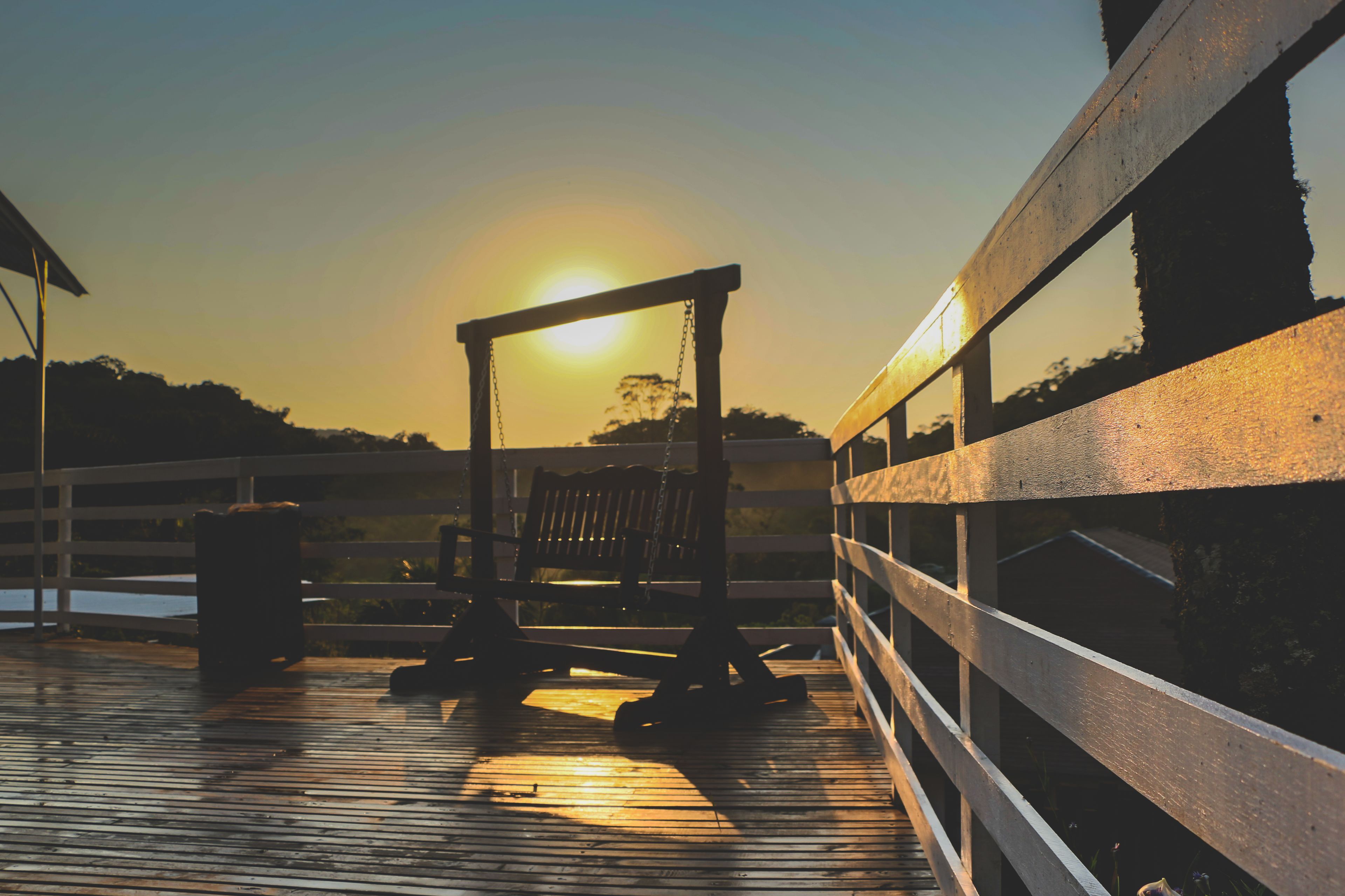 A wooden deck with a metal railing, a bench, and a trash can.