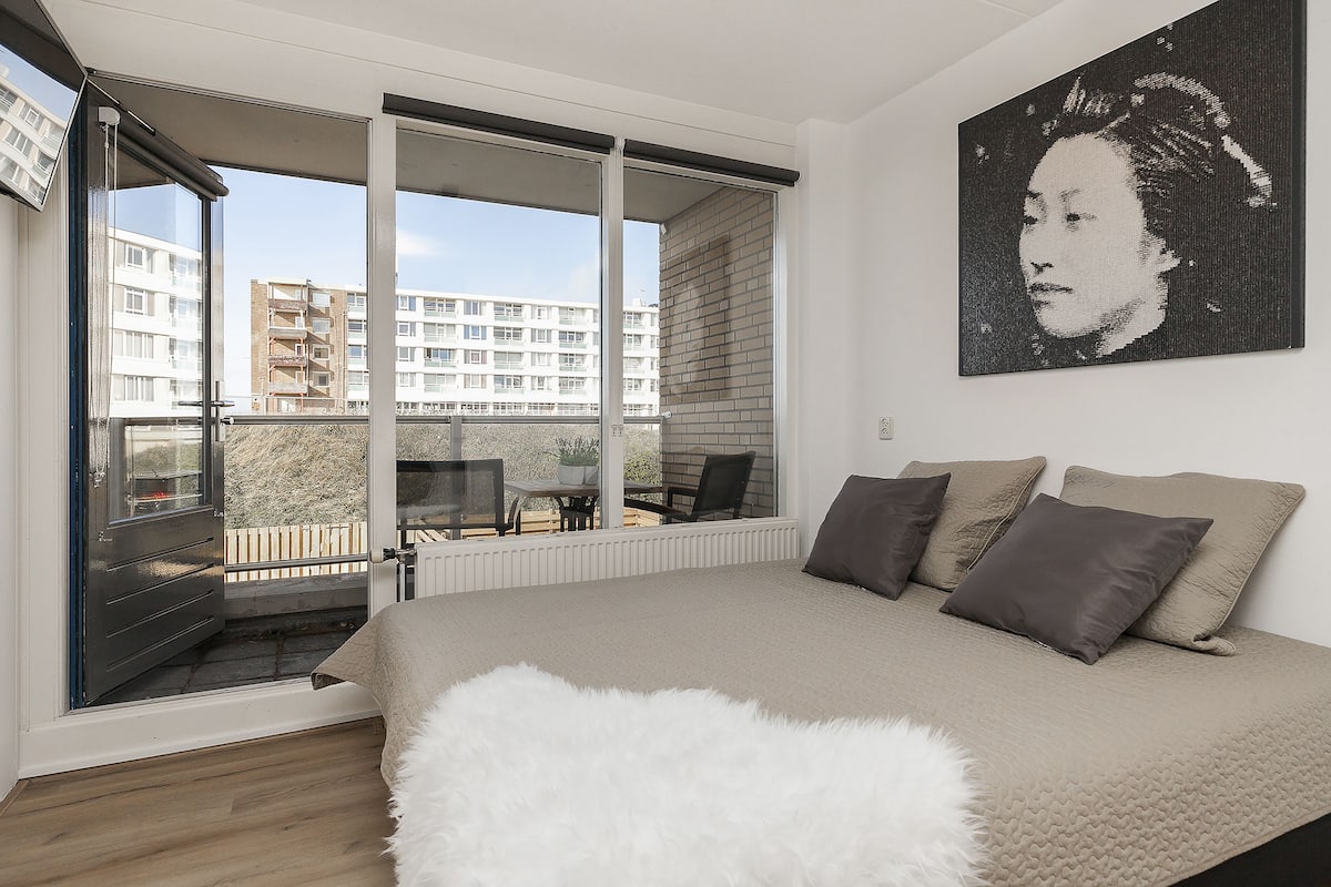 Ein Schlafzimmer mit einem großen Bett, Balkonblick und einem Bild an der Wand.