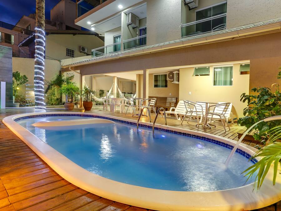 Una piscina con cubierta de madera, rodeada de sillones de descanso y plantas en macetas.