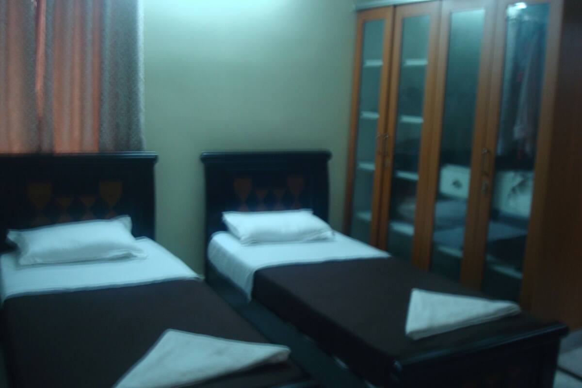 A room with two beds, a wardrobe, and a mirror.