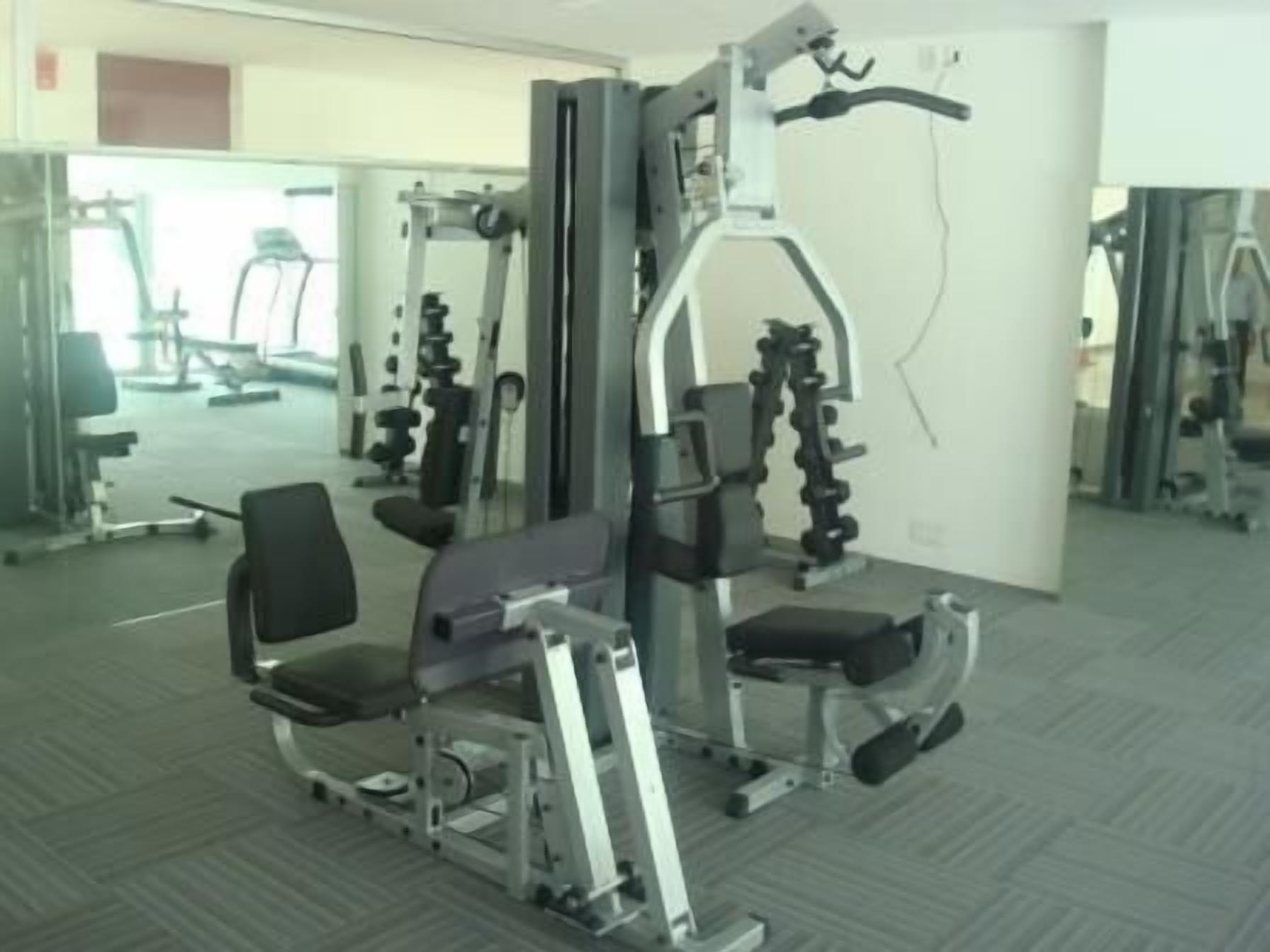 Een sportschool met diverse fitnessapparaten, waaronder een squatrek en een bankdrukpers.
