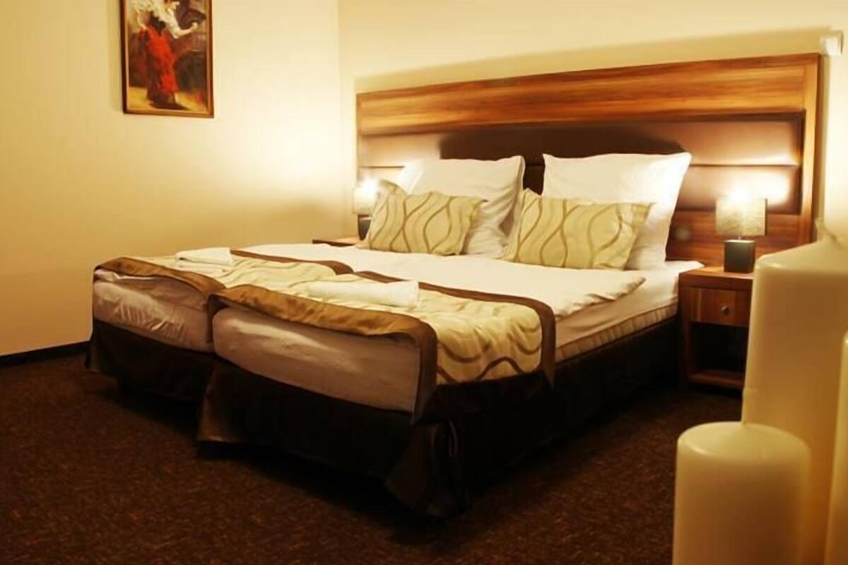 Une chambre d’hôtel avec un grand lit, une tête de lit en bois, une table de chevet avec une lampe et un tableau au mur.