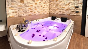 A modern bathroom with a freestanding bathtub, stone wall backsplash, and wooden flooring. - Bakırköy DES Suit Otel (Istanbul)