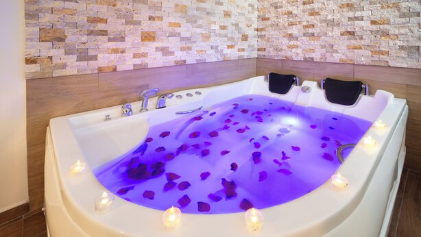 A bathtub filled with water and rose petals, surrounded by candles. - Bakırköy DES Suit Otel (Istanbul)