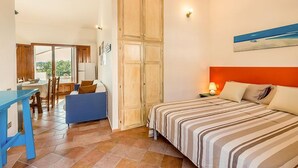 Ein Schlafzimmer mit einem Bett, einem Schreibtisch und einem Stuhl. Eine Schiebetür führt zu einem Balkon.