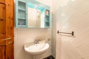 A bathroom with a white sink, a wooden door, and a blue-framed medicine cabinet.