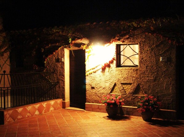 A stone building with a door and a window, surrounded by potted plants.