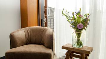 Een bruine lederen stoel, een houten kruk en een vaas met bloemen.