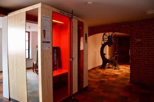 Una habitación con un separador de madera, una zona iluminada con luz roja y una gran rueda mecánica.