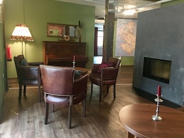 Una habitación acogedora con sillones de cuero, una mesa de madera, una lámpara, un espejo y un mapa en la pared.