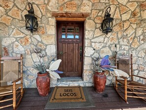 A stone facade with a wooden door, two lanterns, and decorative plants.
