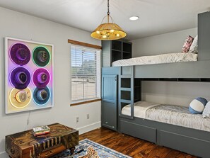 Habitación con literas, una lámpara en el techo, un reloj en la pared y una ventana con persianas.
