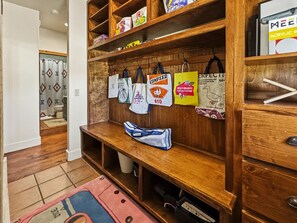 Un banco de madera con una bolsa azul, un estante con varias bolsas y una pared de madera.
