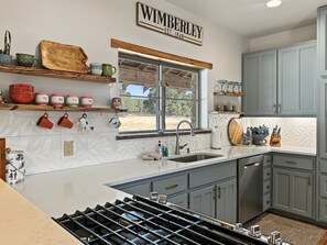 Una cocina con estufa a gas, un lavamanos y una ventana que ofrece vistas al exterior.
