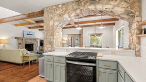 A kitchen with stone walls, wooden beams, and a built-in oven.