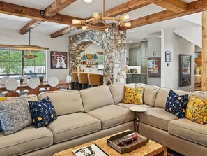 Una sala moderna con un sofá modular, una zona de comedor y una cocina al fondo.