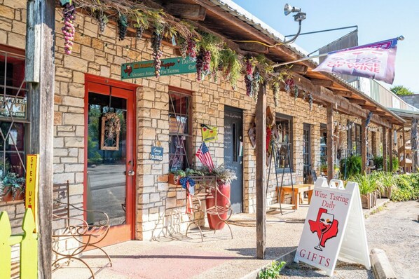 Um edifício rústico com fachada de pedra, porta vermelha e placa indicando degustação de vinhos diária.