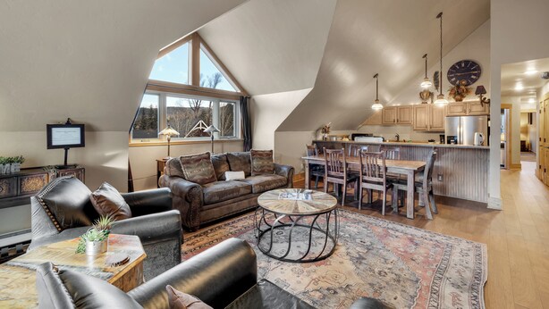 A spacious loft with a high ceiling, a cozy seating area with leather furniture, a dining table, and a kitchen with wooden cabinets. - Downtown Location - Steps to Gondola, Hot Tub, DOG FRIENDLY SCC3 (Breckenridge)