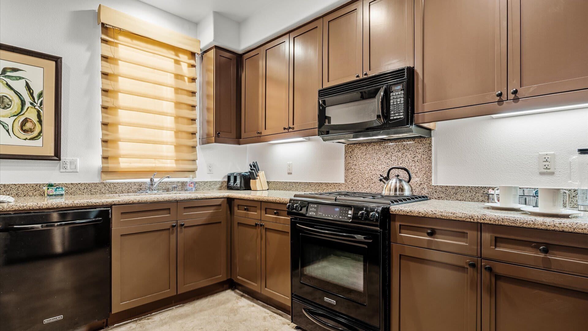 Una cocina con armarios de madera, una estufa, un microondas y un hervidor.
