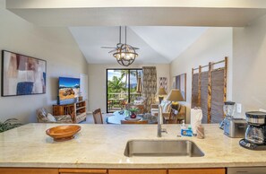 A modern kitchen with a central island, a dining area with a view, and a living space with a ceiling fan.