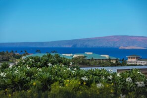 A coastal hotel with a view of the ocean and a mountain in the background.