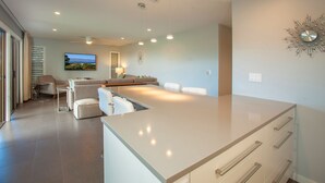 Een moderne keuken met een centraal eiland, een zithoek met een bank en uitzicht op de omgeving.