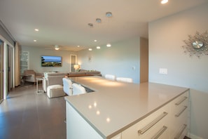 Een moderne keuken met een centraal eiland, een zithoek met een bank en uitzicht op de omgeving.