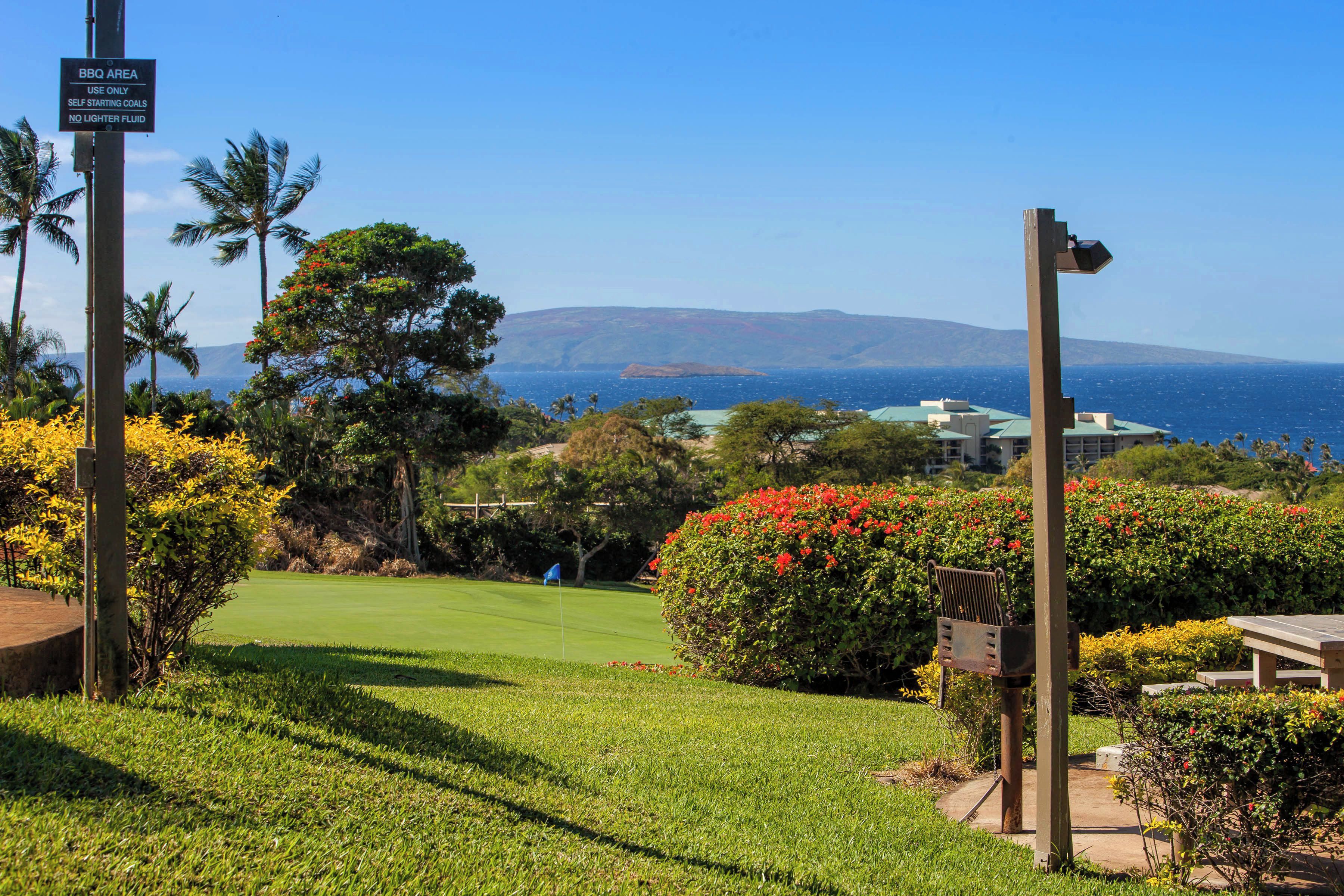 A golf course with a sign indicating a BBQ area and a view of the ocean.