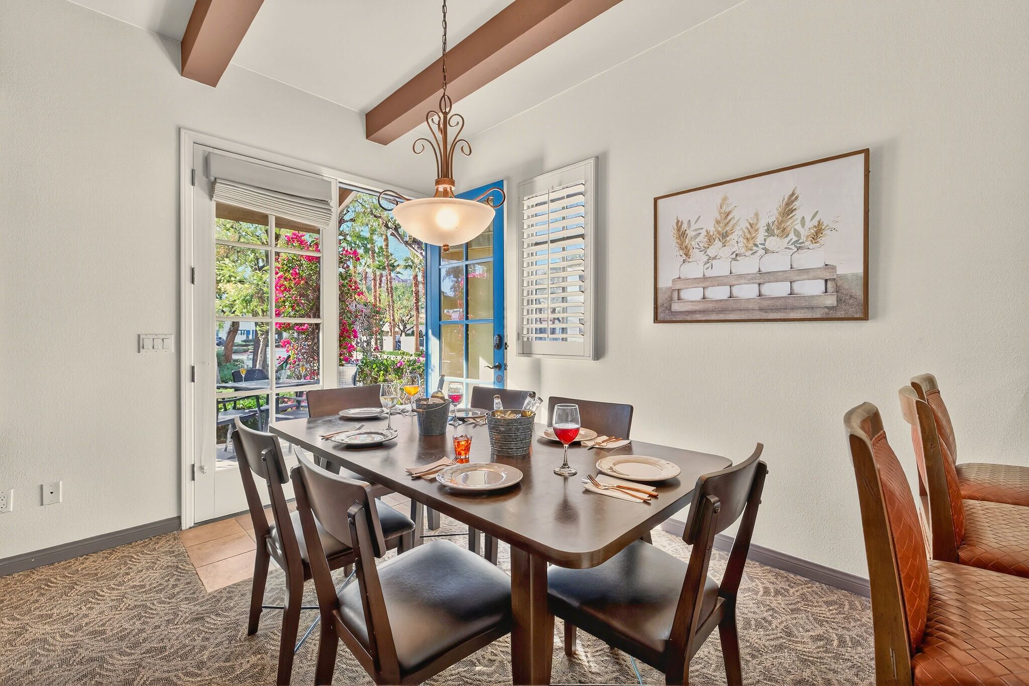 A dining area with a wooden table, dark chairs, and a hanging light fixture.
