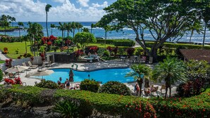 A pool area with a hot tub, lounge chairs, and a view of the ocean.