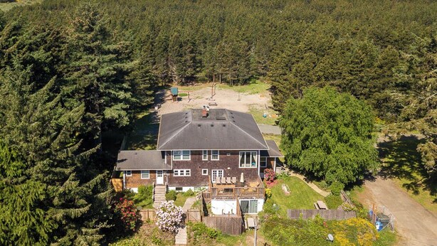 A two-story house with a large deck, surrounded by dense forest, near a beach. - Antique, HOT TUB, Game Room, Theater, Dogs Ok (Bloom) (Seaview)