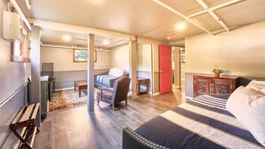 A cozy, well-lit room with a bed, a chair, a desk, and a red door leading to another room. - Antique, HOT TUB, Game Room, Theater, Dogs Ok (Bloom) (Seaview)