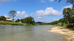 A riverbank with houses on the left and trees on the right.
