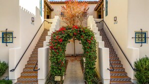 Eine Treppe mit einem floralen Bogen, gemusterten Fliesen und einer Fassade mit dekorativen Elementen.