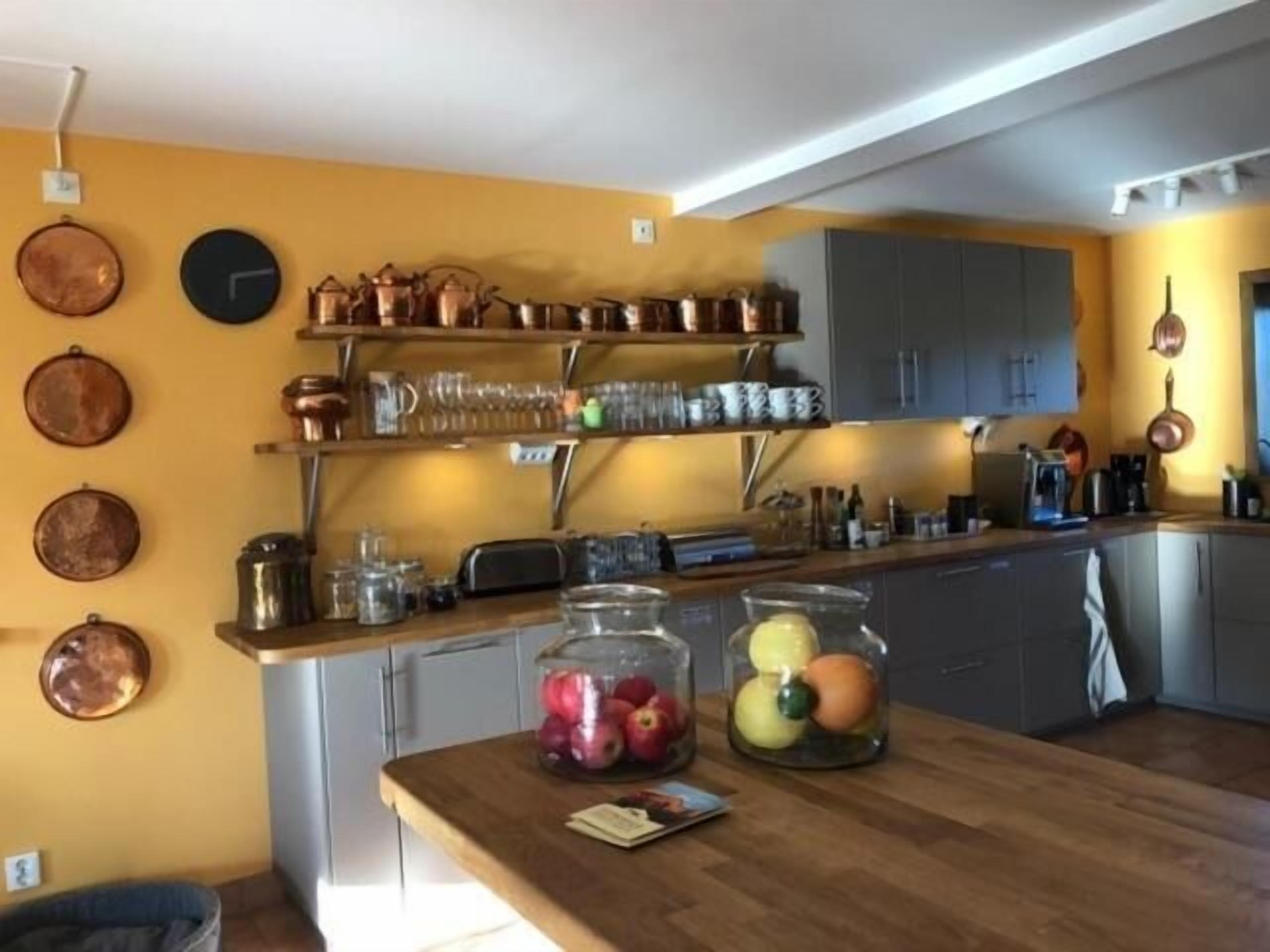 Een keuken met koperen pannen, glazen potten en een houten aanrecht.