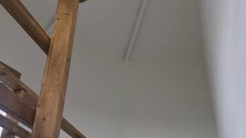 A wooden staircase leading to a white ceiling with a light fixture.