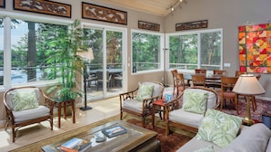 A spacious living room with a large glass door leading to a deck, wooden furniture, and a view of the outdoors. - San Juan Island, Roche Harbor Overlook #196 (Roche Harbor)