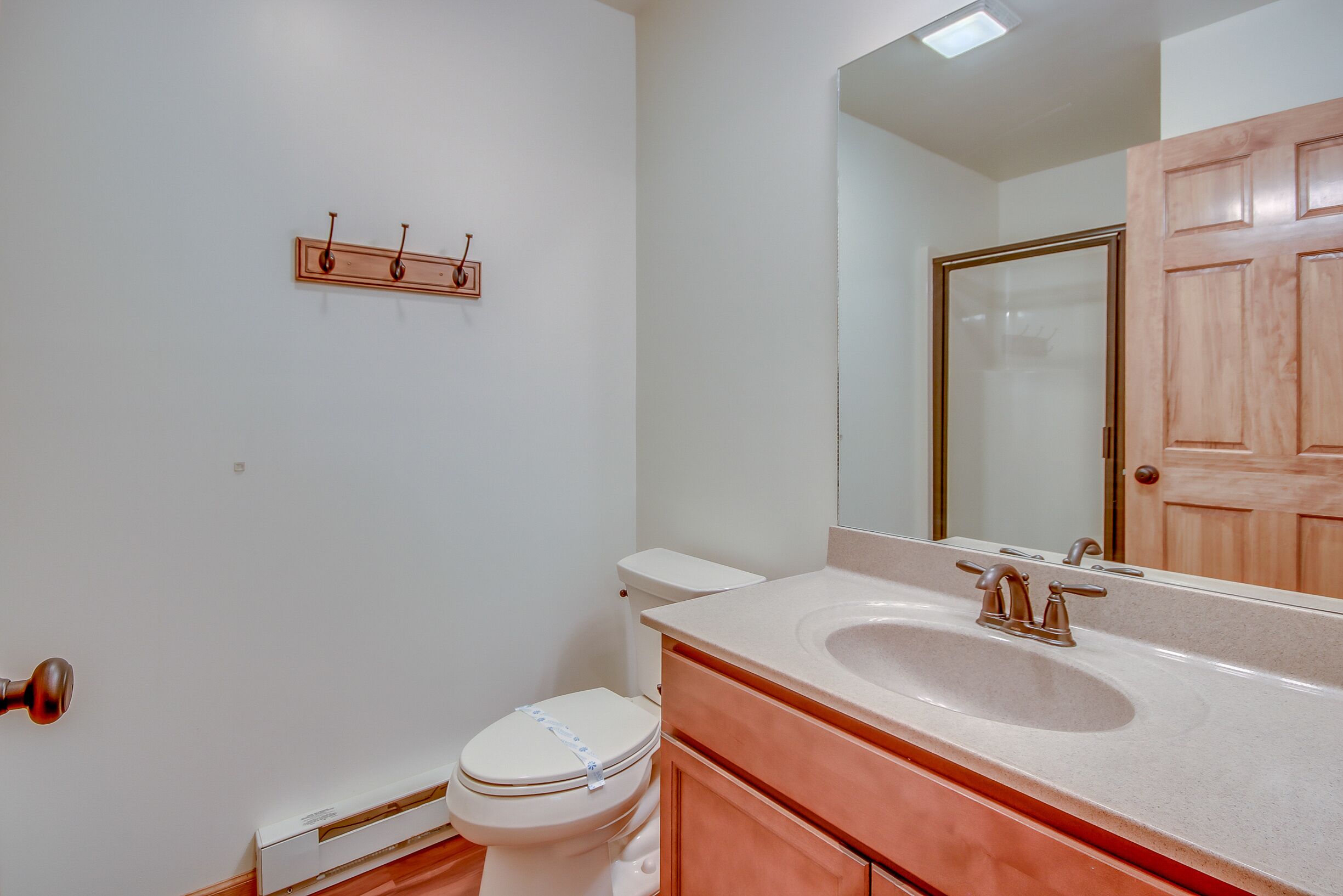 Une salle de bain avec des toilettes blanches, un lavabo avec un miroir au-dessus et une porte en bois.
