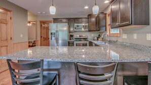 A modern kitchen with granite countertops, stainless steel appliances, and dark wood cabinets.