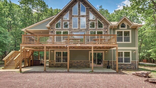 Een twee verdiepingen tellend huis met een balkon, een overdekte veranda en een gevel van natuursteen.