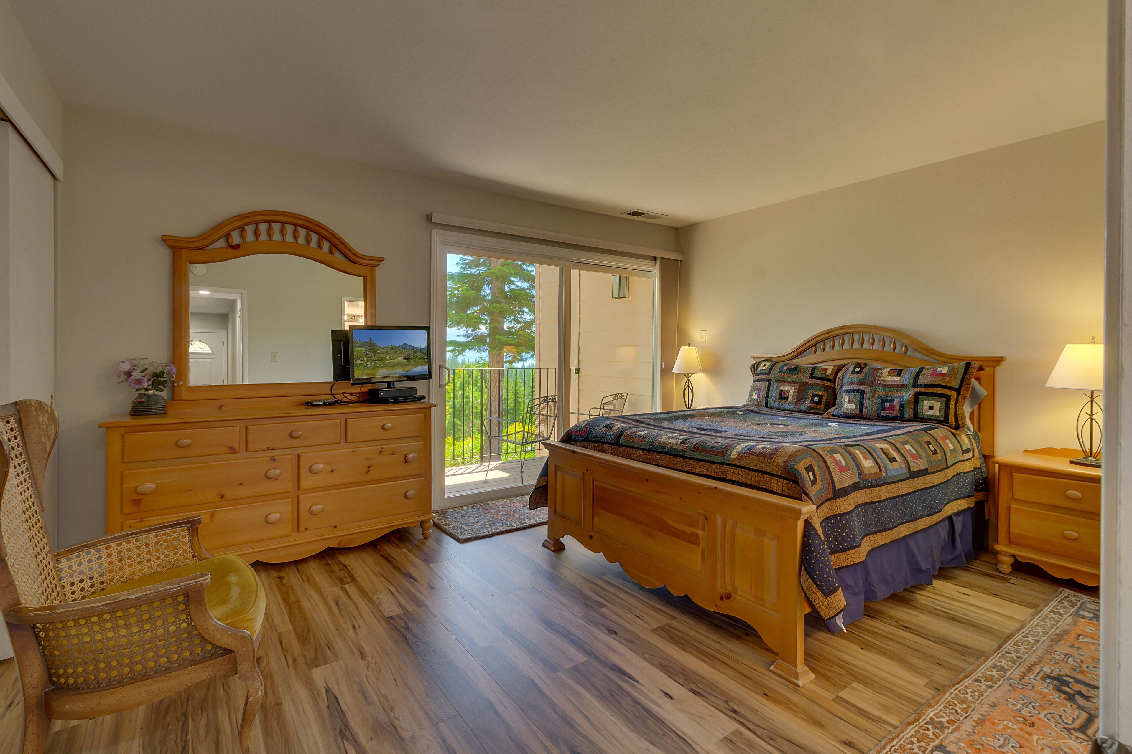 Une chambre à coucher avec un lit en bois, une commode, une chaise et un grand miroir.