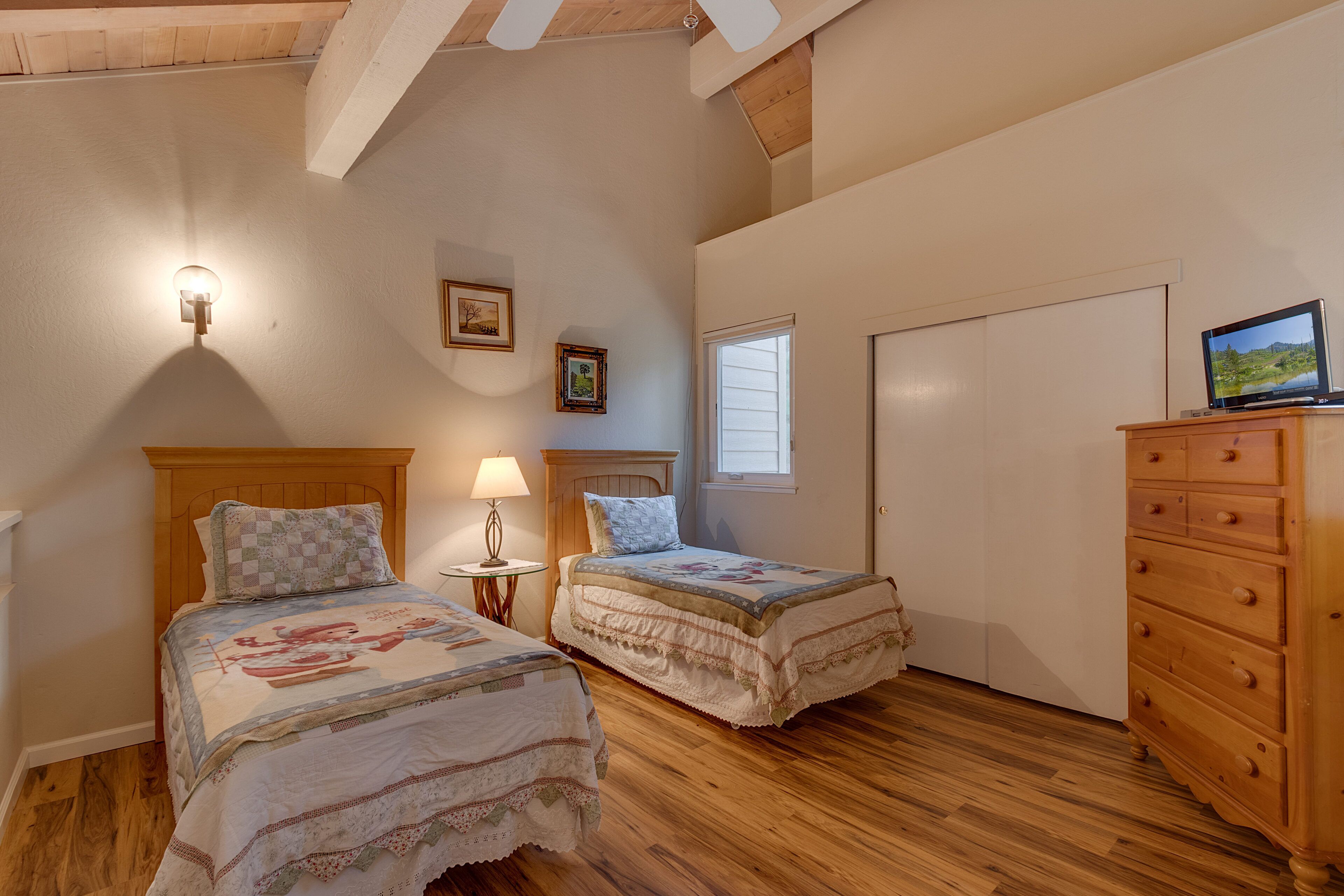 Un dormitorio con dos camas, un aparador de madera, una lámpara y un televisor.