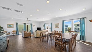 Ein geräumiges Wohnzimmer mit Essbereich, großen Fenstern und Deckenventilator.