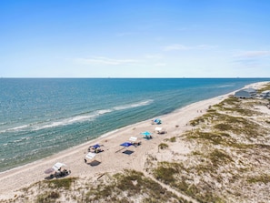 A beach with tents and a building. - Sea Turtle | 6BR/5.5BA Fort Morgan Beach Home | Sleeps 17 | Gulf & Bay Views (Gulf Shores)