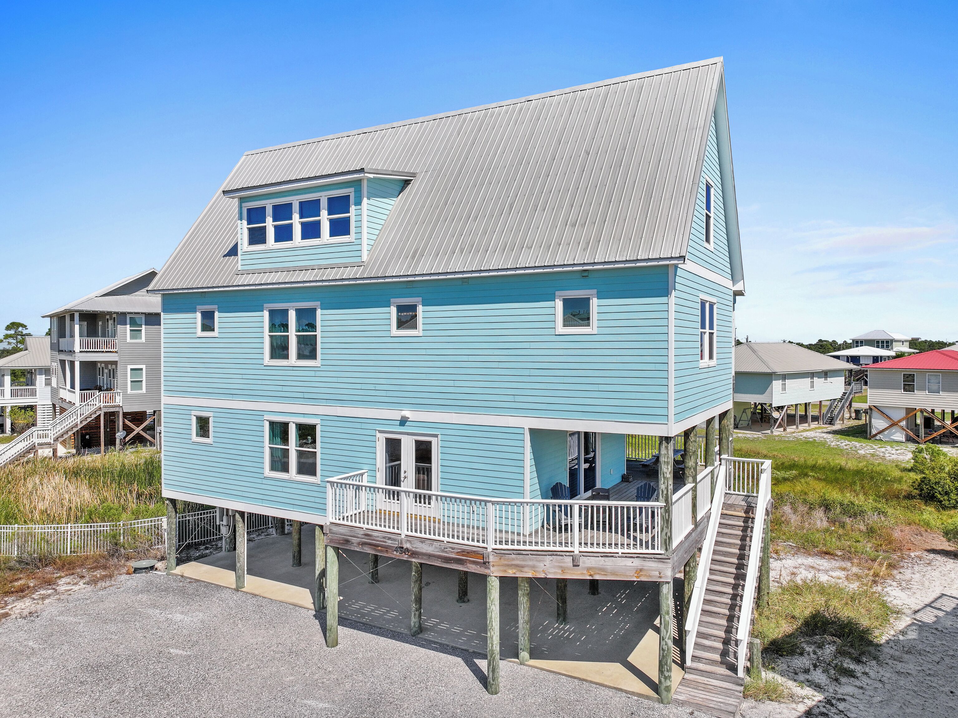 Une maison à deux étages située en bord de mer, dotée d’un balcon, d’une véranda et d’un escalier menant à l’étage supérieur.