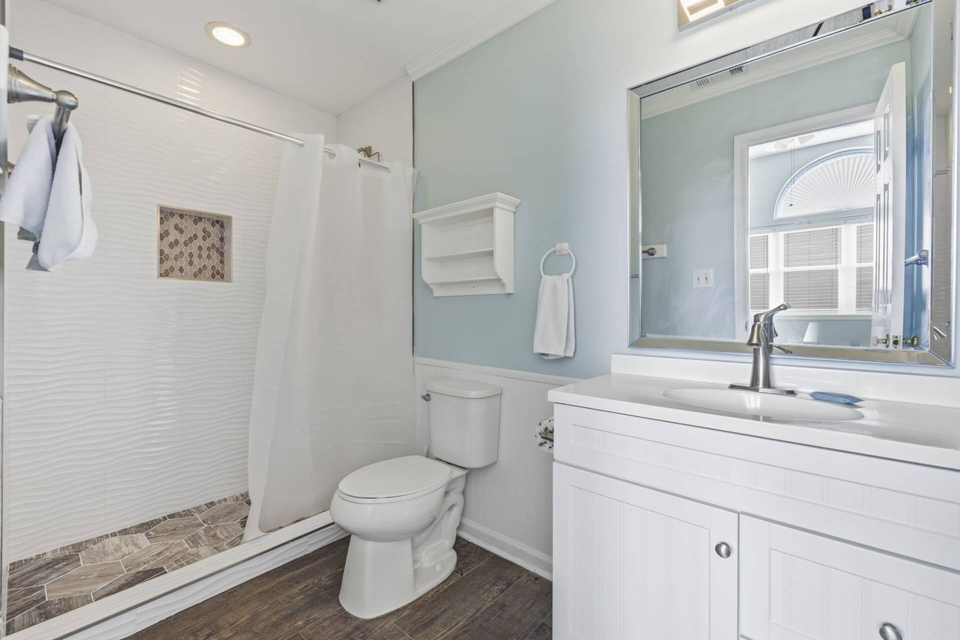 Une salle de bain équipée d’une douche, de toilettes, d’un lavabo et d’un grand miroir.